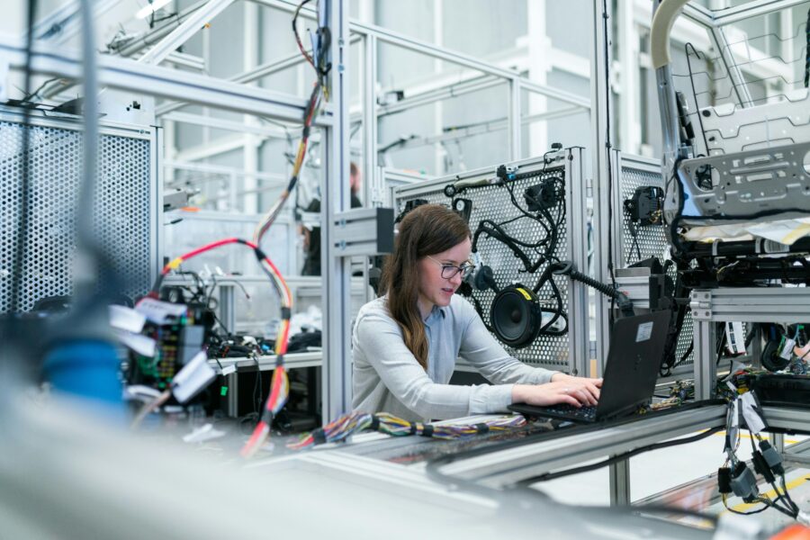 A young woman works at her laptop in an engineering facility
