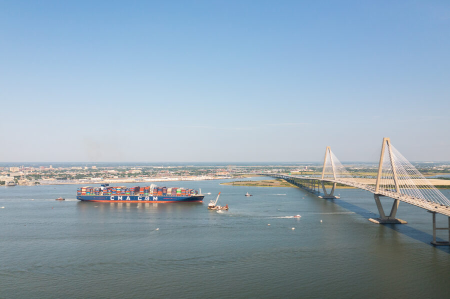 A cargo ship sails by the Ravenel Jr. Bridge in South Carolina at dusk.