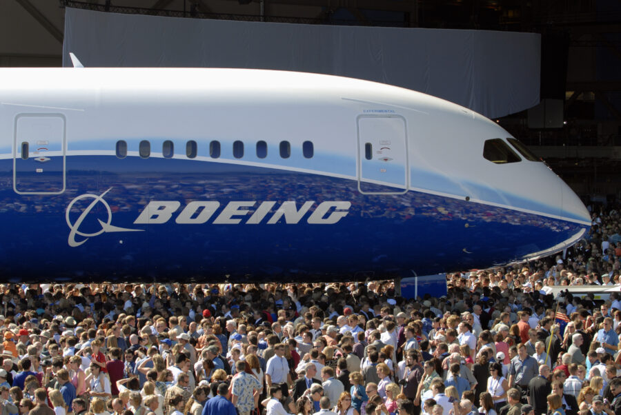 A crowd of people stands around a Boeing aircraft to celebrate the rollout of a new aircraft model.