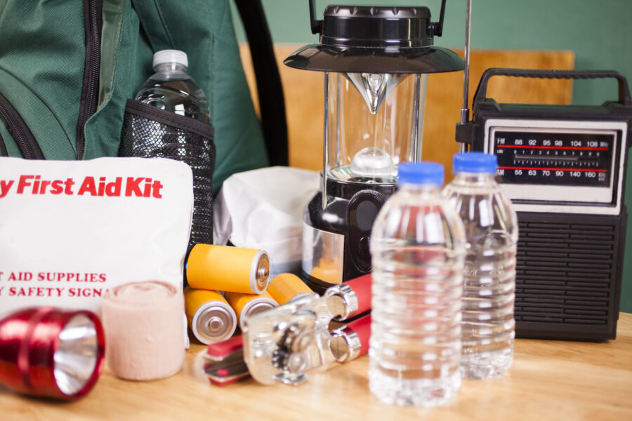 A close-up of emergency preparedness equipment, such as a backpack, water bottles, lantern, and radio.