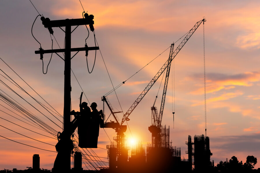 Silhouette of electricians using a cable car to maintain a high voltage line system.
