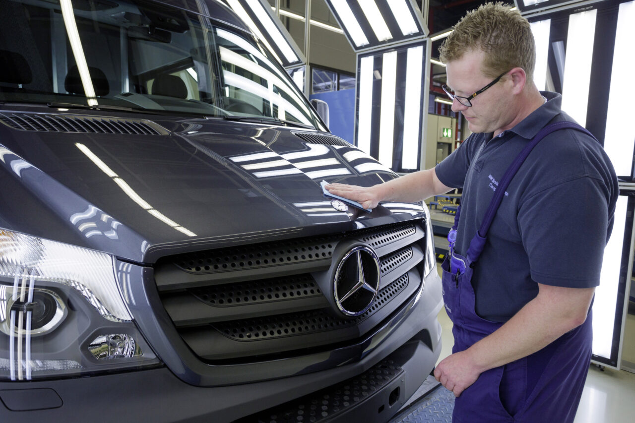 A worker wipes down the front of a Daimler Sprinter van in the manufacturing facility.