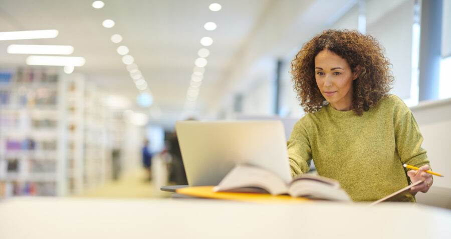 A woman uses her laptop while in a library.