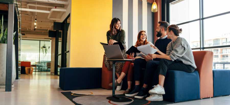 A group of young coworkers sit together in a colorful office.