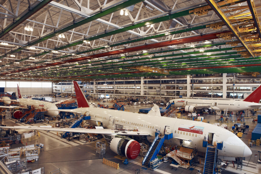 Three passenger aircrafts sit in a large hangar.