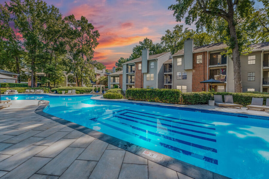 A large swimming pool in an apartment complex during the evening.