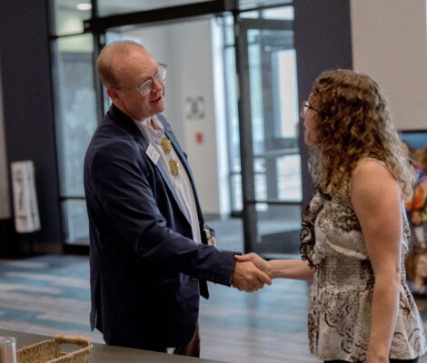 A business man shakes hands with a colleague at an event.