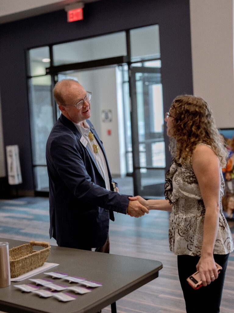 A business man shakes hands with a colleague at an event.